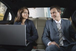 Business people in maxi taxi using laptop